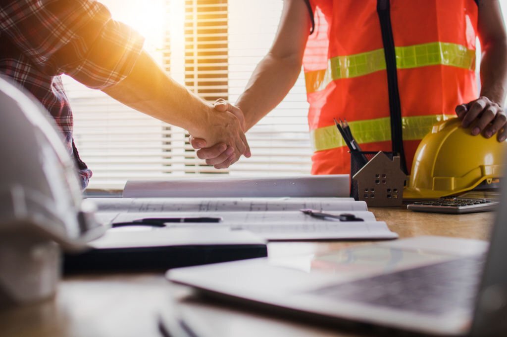 Handshake of two business man, after  architect working and planning blueprint, Engineering objects on workplace